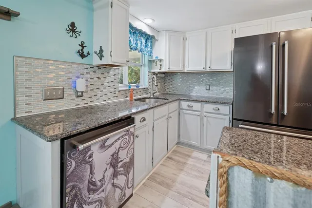 a kitchen with stainless steel appliances granite countertop a refrigerator and a sink