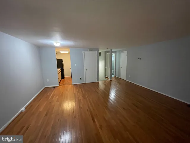 a view of a big room with wooden floor and windows