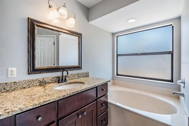 a bathroom with a granite countertop sink mirror and a bathtub