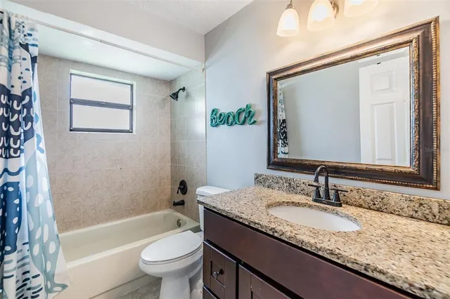 a bathroom with a granite countertop sink a toilet and a large mirror