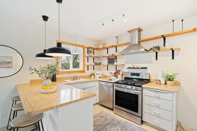 a kitchen with a sink a stove and chairs with wooden floor