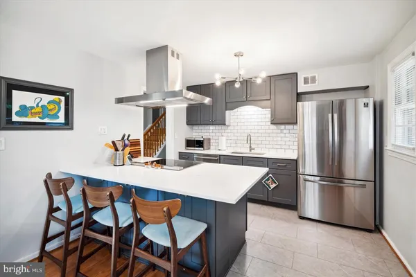 a kitchen with stainless steel appliances kitchen island granite countertop a dining table chairs and a refrigerator