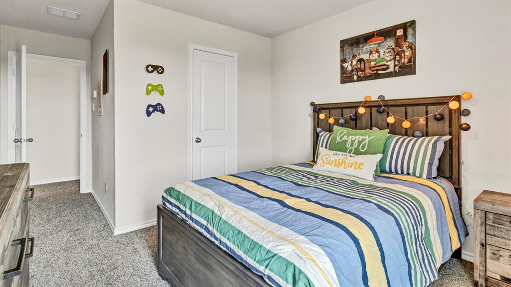 124 Pheasant Run Road Terrell, TX 75160 - Photo 12 of 35 Bedroom featuring neutral wall paint, gray textured carpeting, a solid-panel door, baseboard trim, and a wood-finish bed frame with headboard