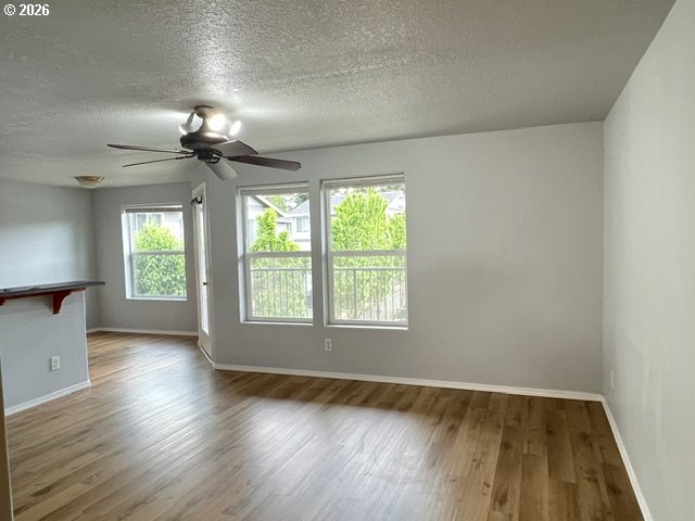 659 Northeast 162nd Avenue, Unit 302 Portland, OR 97230 - Photo 5 of 17 an empty room with wooden floor chandelier fan and windows