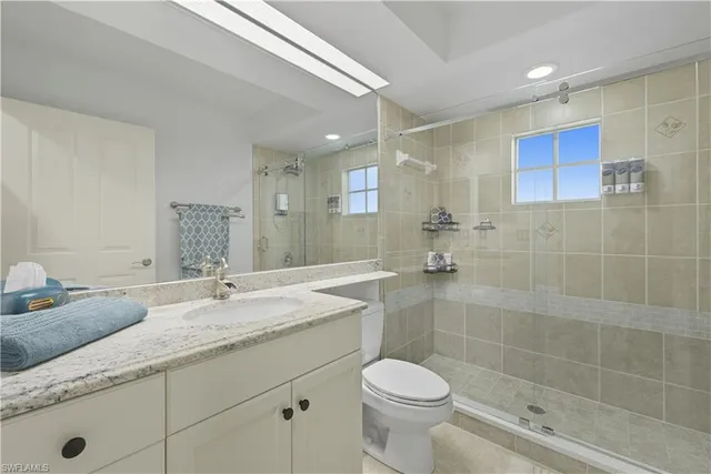 a bathroom with a granite countertop sink a toilet a mirror and shower
