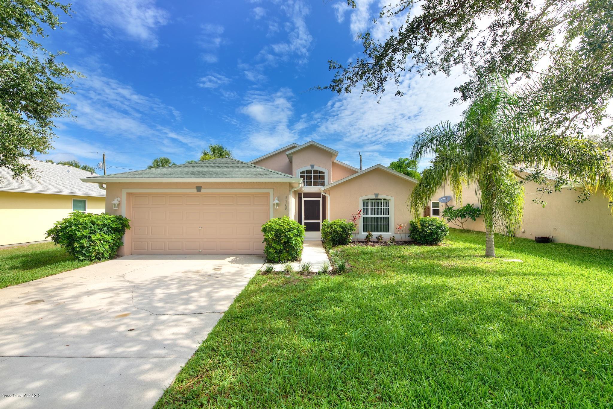 1768 Palm Ridge Road Melbourne, FL 32935 - Photo 1 of 20 a front view of a house with a yard and garage