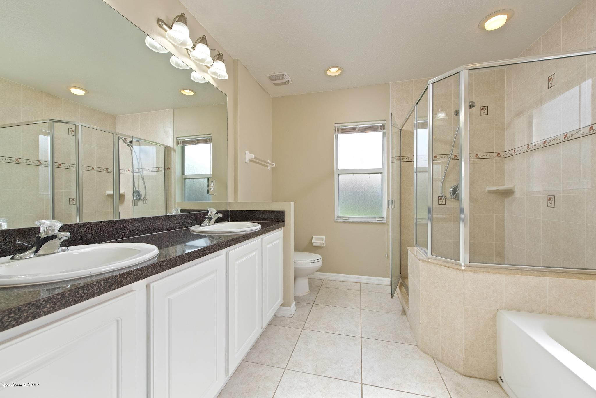 1768 Palm Ridge Road Melbourne, FL 32935 - Photo 11 of 20 a spacious bathroom with a granite countertop sink a toilet a mirror and shower