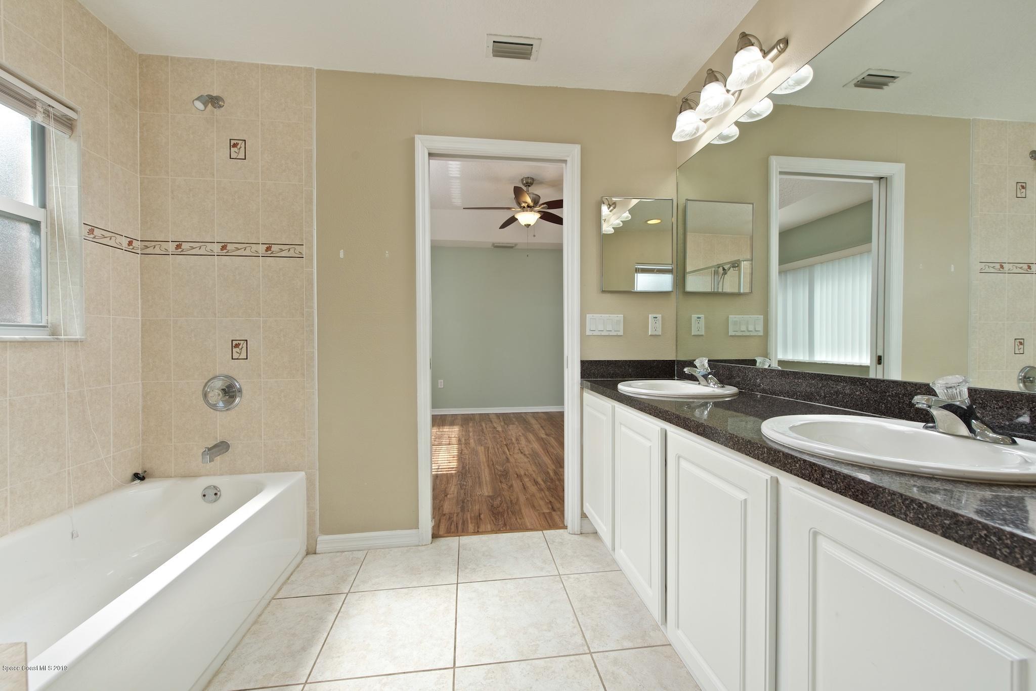 1768 Palm Ridge Road Melbourne, FL 32935 - Photo 12 of 20 a spacious bathroom with a granite countertop sink a mirror a bathtub and shower