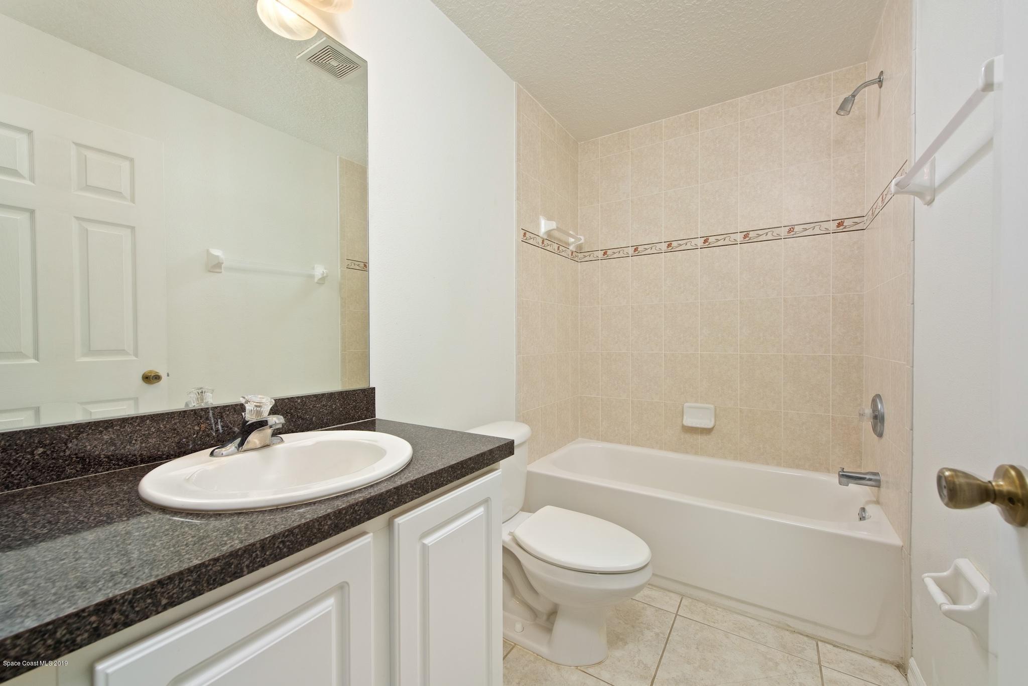 1768 Palm Ridge Road Melbourne, FL 32935 - Photo 15 of 20 a bathroom with a granite countertop sink toilet a mirror and shower
