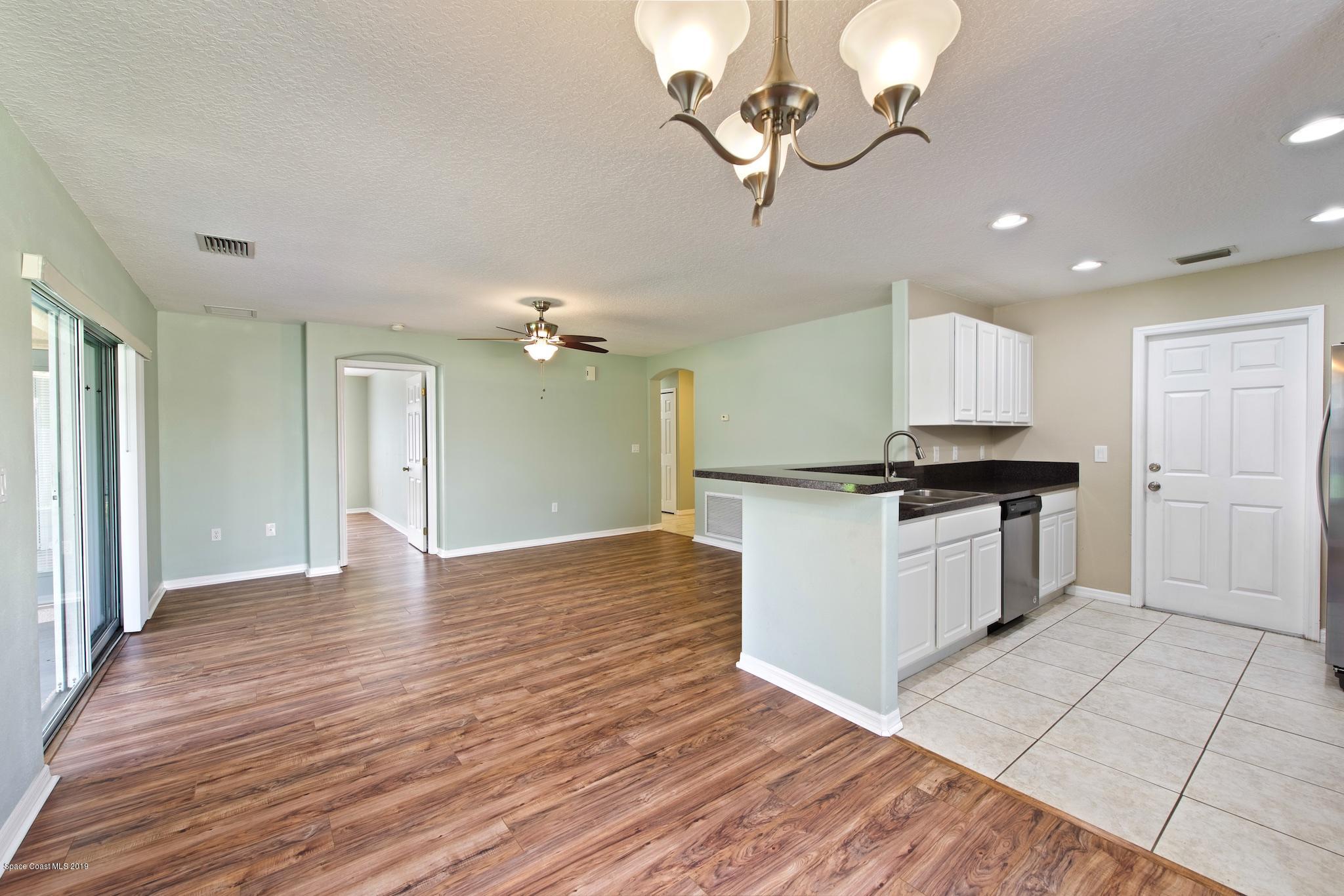 1768 Palm Ridge Road Melbourne, FL 32935 - Photo 3 of 20 a kitchen with a refrigerator and white cabinets