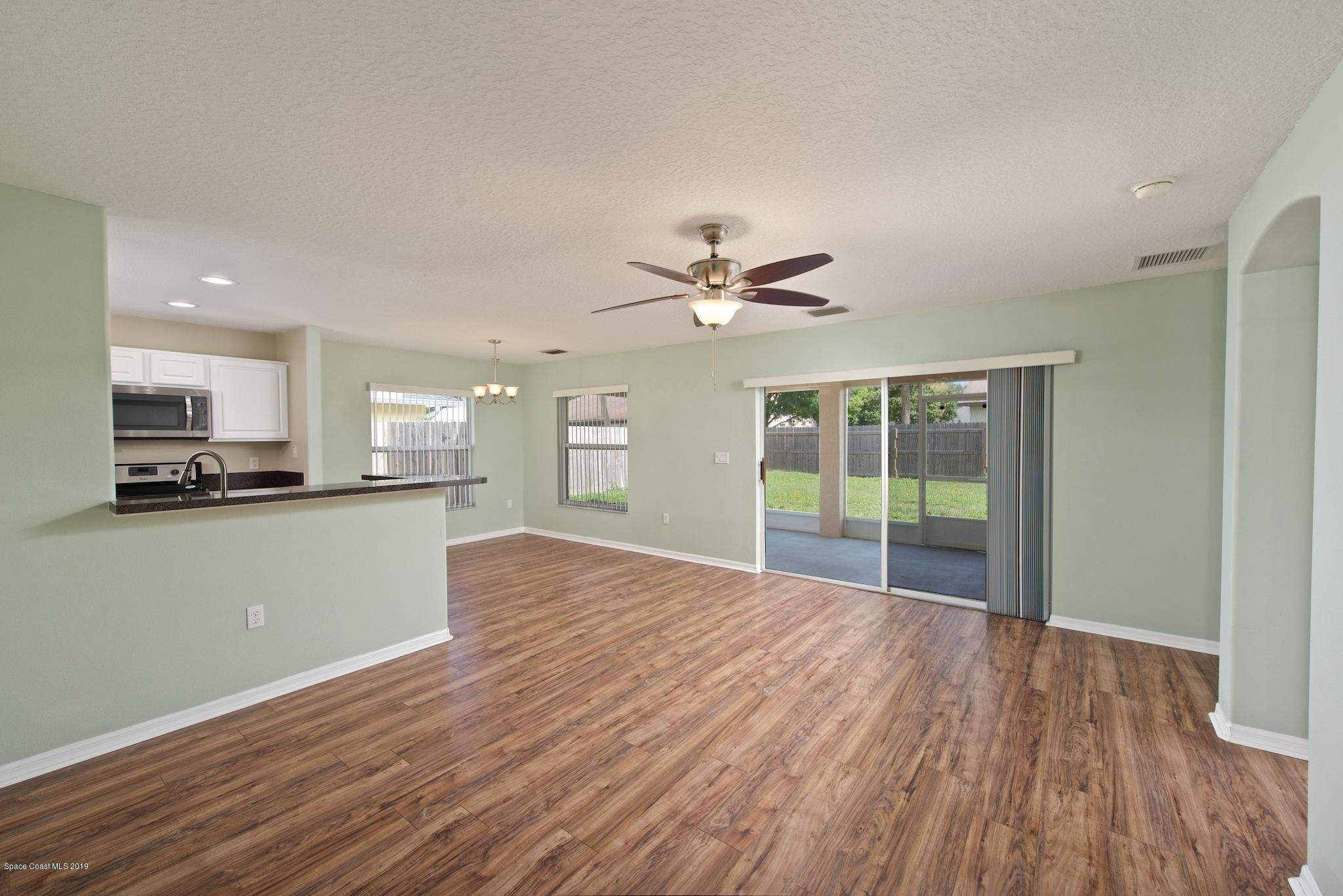 1768 Palm Ridge Road Melbourne, FL 32935 - Photo 6 of 20 a view of empty room with wooden floor and fan