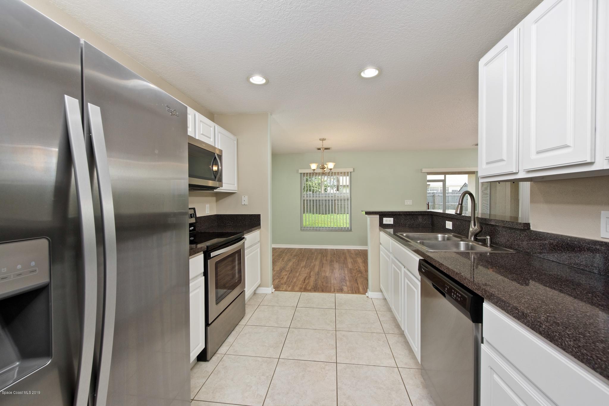 1768 Palm Ridge Road Melbourne, FL 32935 - Photo 8 of 20 a kitchen with stainless steel appliances granite countertop a sink a stove and a refrigerator