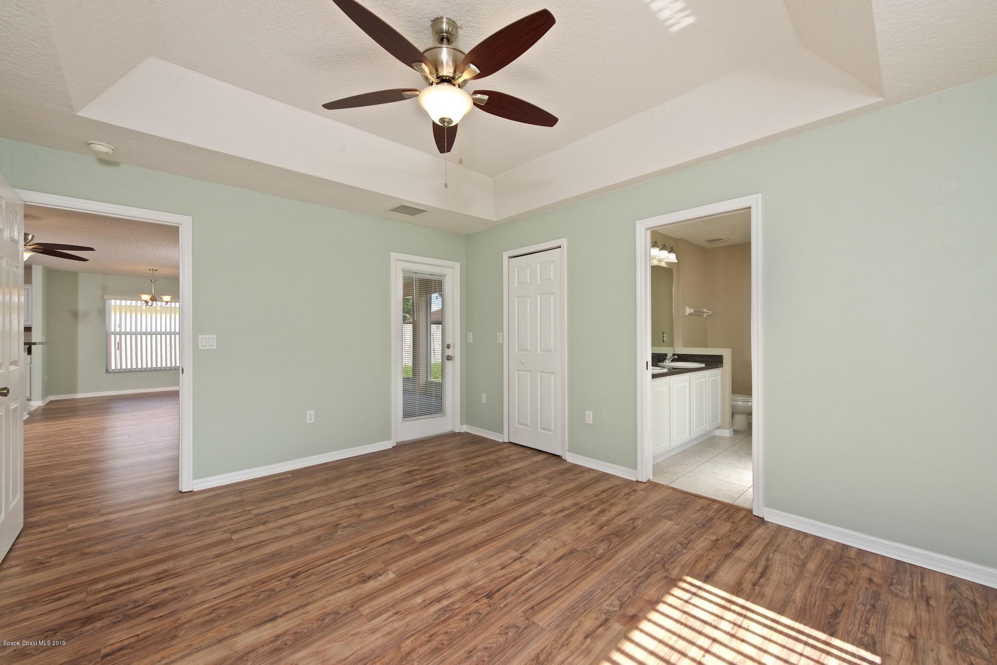 1768 Palm Ridge Road Melbourne, FL 32935 - Photo 9 of 20 a view of a big room with wooden floor and a ceiling fan