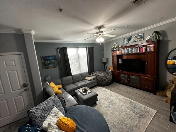 a living room with furniture a flat screen tv and kitchen view