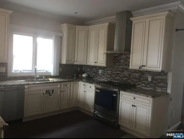 a kitchen with stainless steel appliances granite countertop a sink stove and cabinets