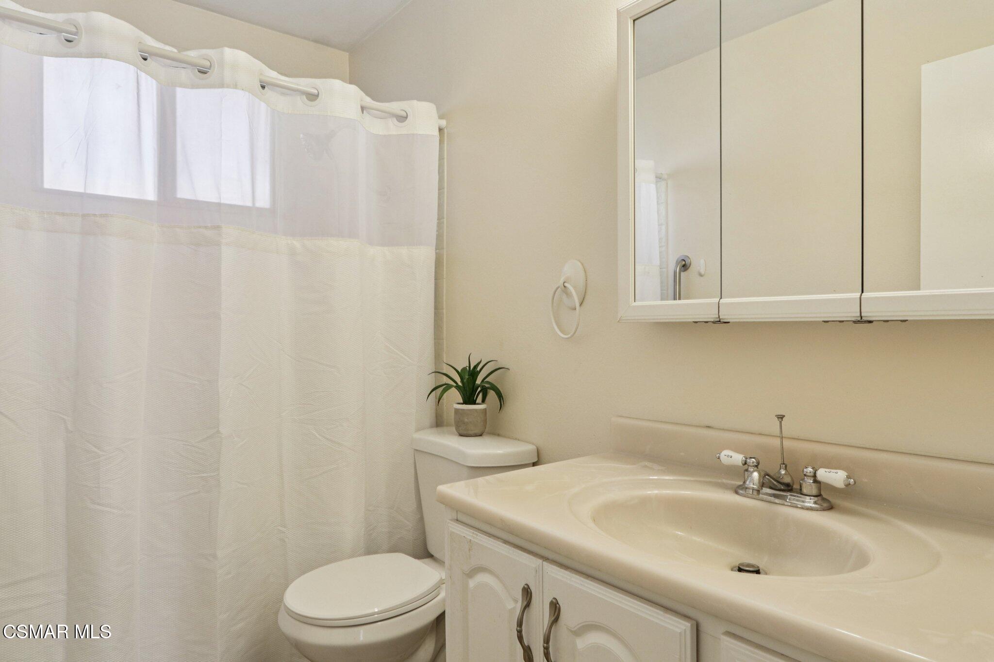 12745 Muscatine Street Pacoima, CA 91331 - Photo 20 of 35 a bathroom with a sink a toilet and shower curtain