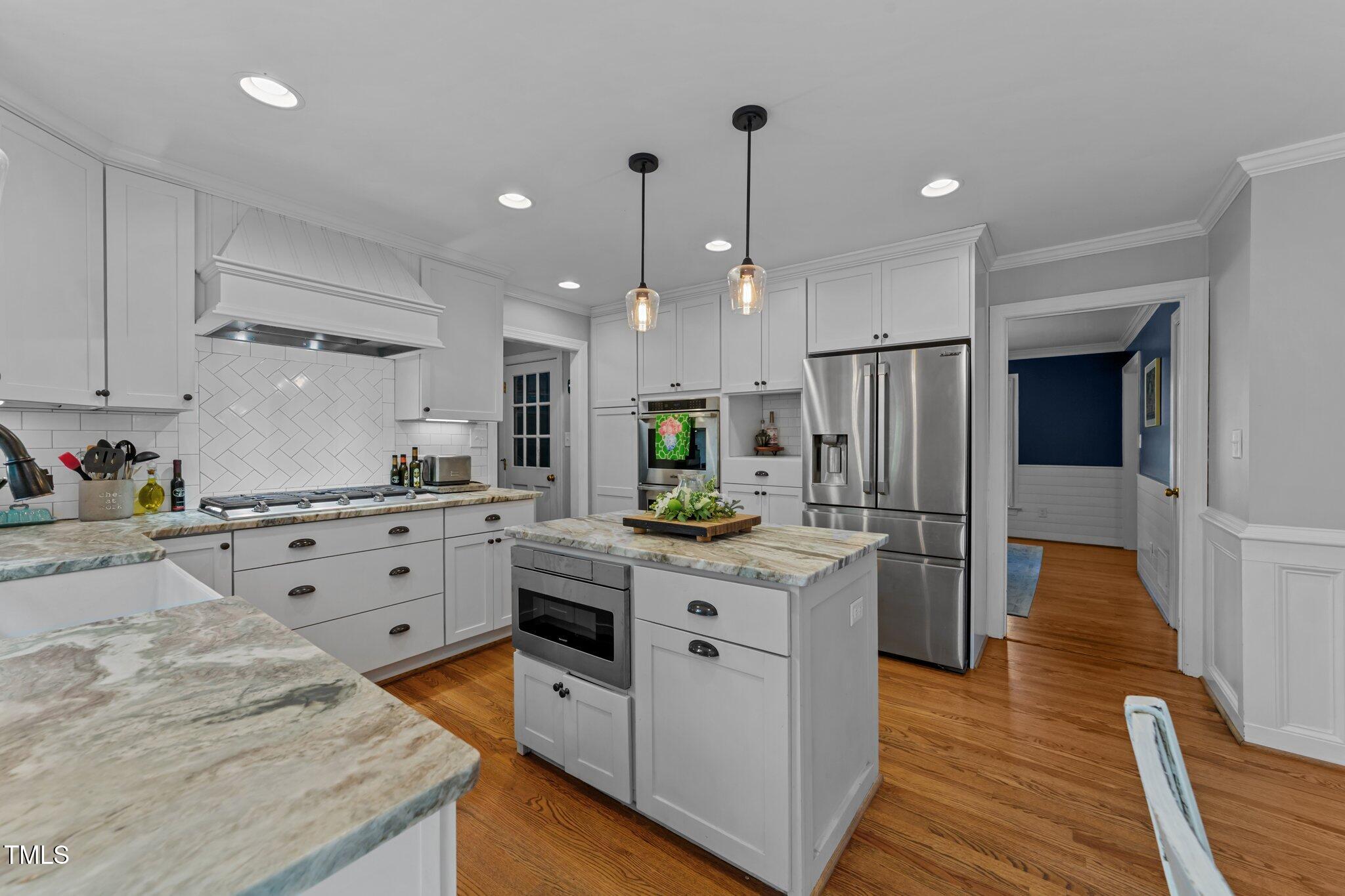 2409 Beechview Court Raleigh, NC 27615 - Photo 15 of 46 a kitchen with stainless steel appliances kitchen island granite countertop a refrigerator a oven and white cabinets with wooden floors
