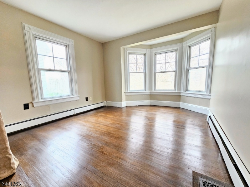 232 Morris Avenue Summit, NJ 07901 - Photo 7 of 13 an empty room with wooden floor and windows with curtains view