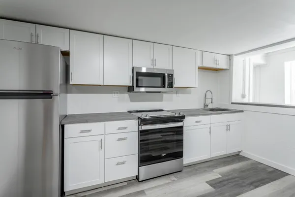 a kitchen with white cabinets and refrigerator