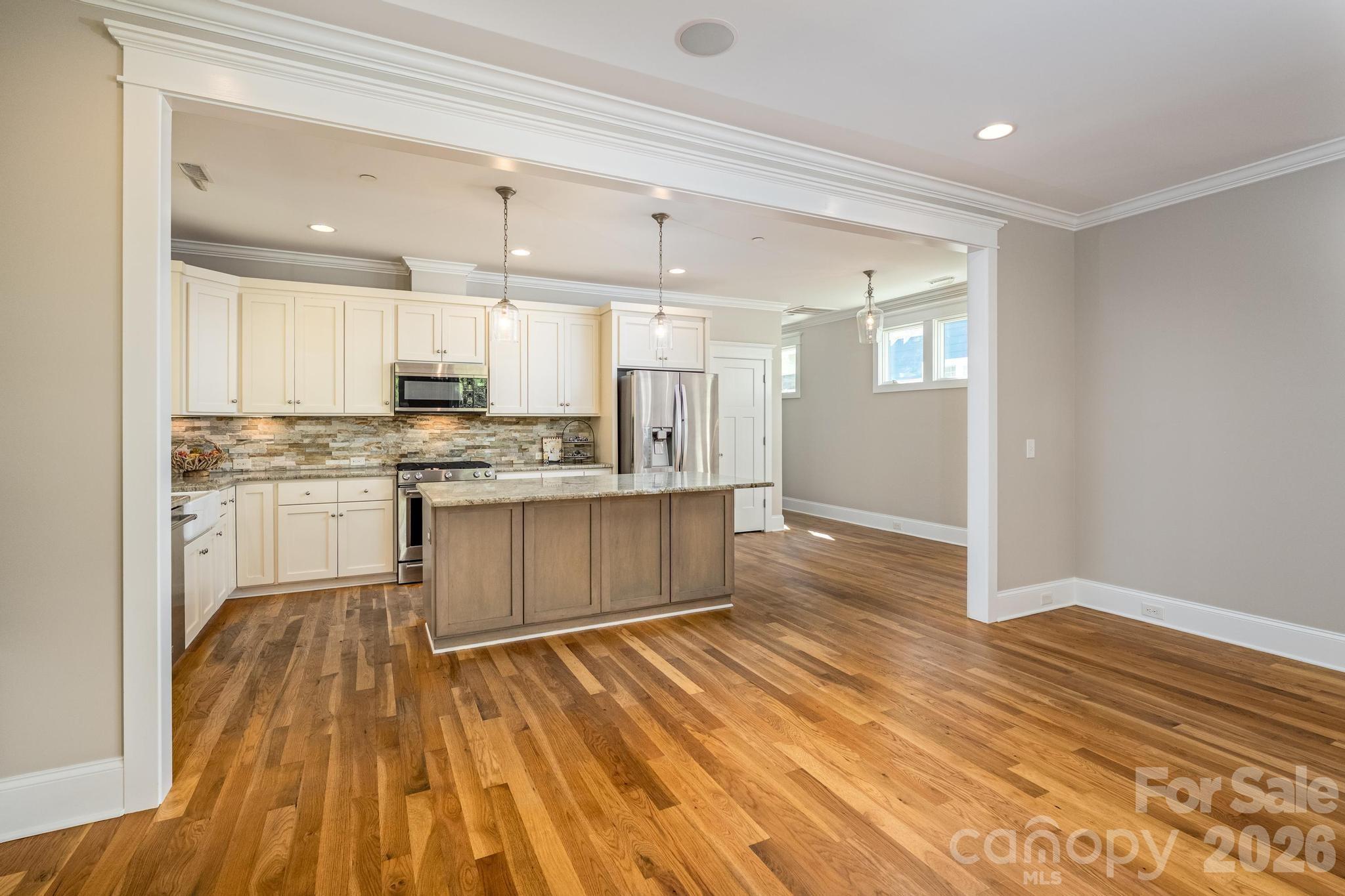 735 Emma Claire Lane Davidson, NC 28036 - Photo 11 of 48 a large kitchen with kitchen island a sink dishwasher a stove and white cabinets with wooden floor