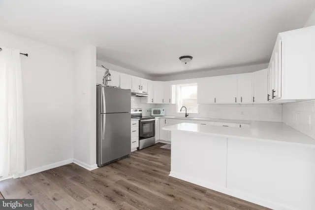 a kitchen with a refrigerator a stove top oven and white cabinets
