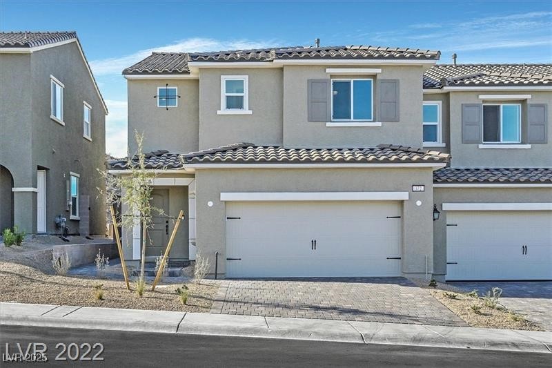 View of front of property featuring stucco siding, a garage, a tile roof, and driveway