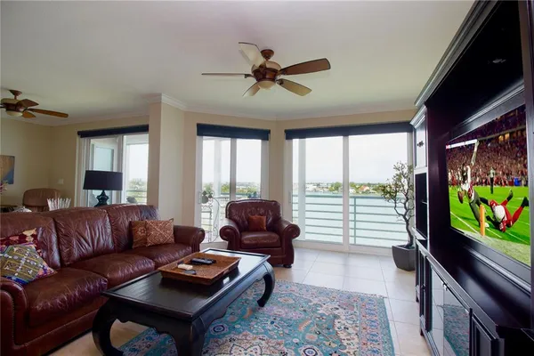 a living room with furniture floor to ceiling window and a flat screen tv