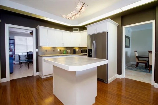 a kitchen with a refrigerator a sink and a dining table with wooden floor