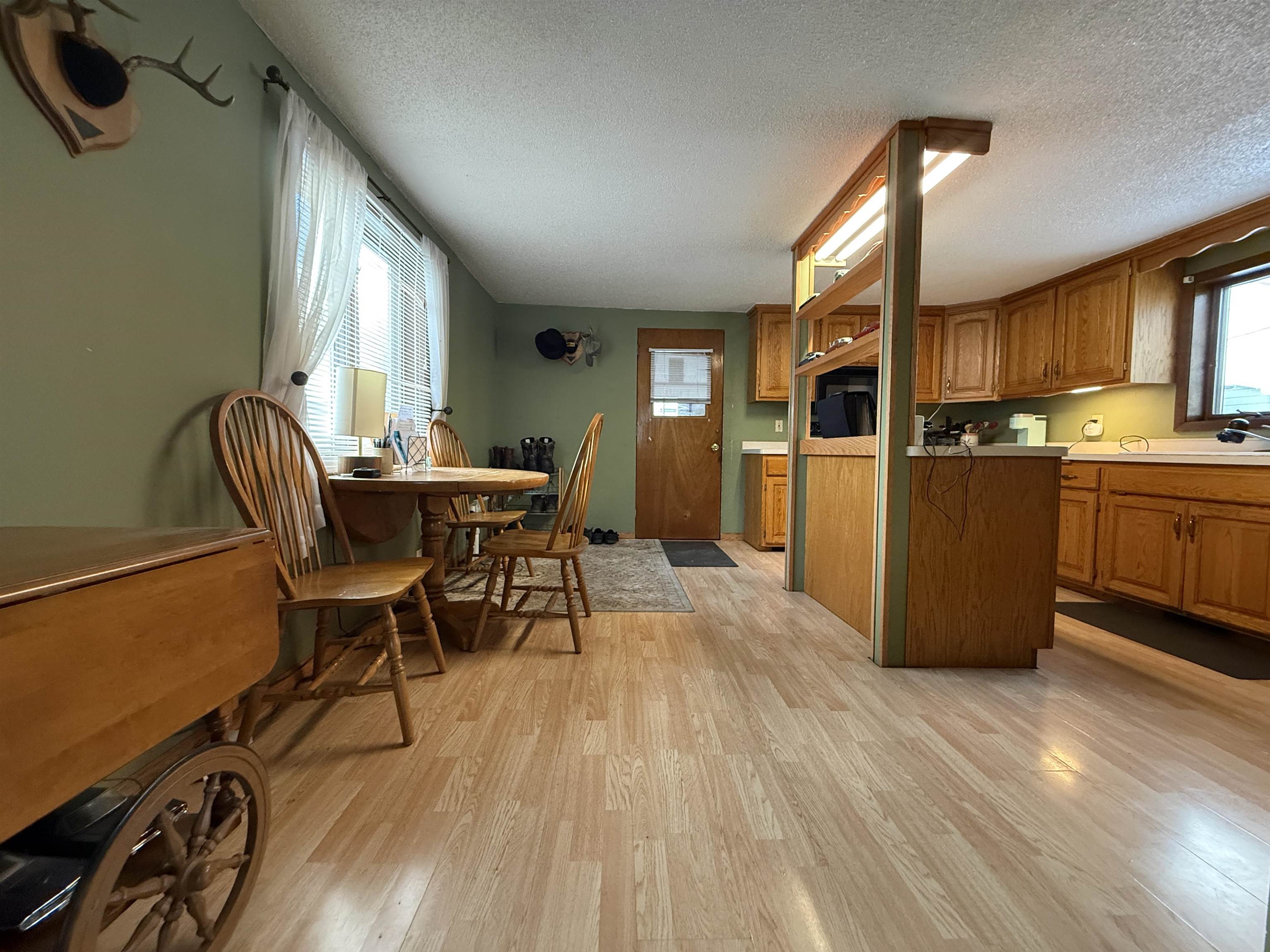 609 8th Street Northwest Chisholm, MN 55719 - Photo 12 of 26 Kitchen with light countertops, light wood finished floors, brown cabinetry, and a textured ceiling