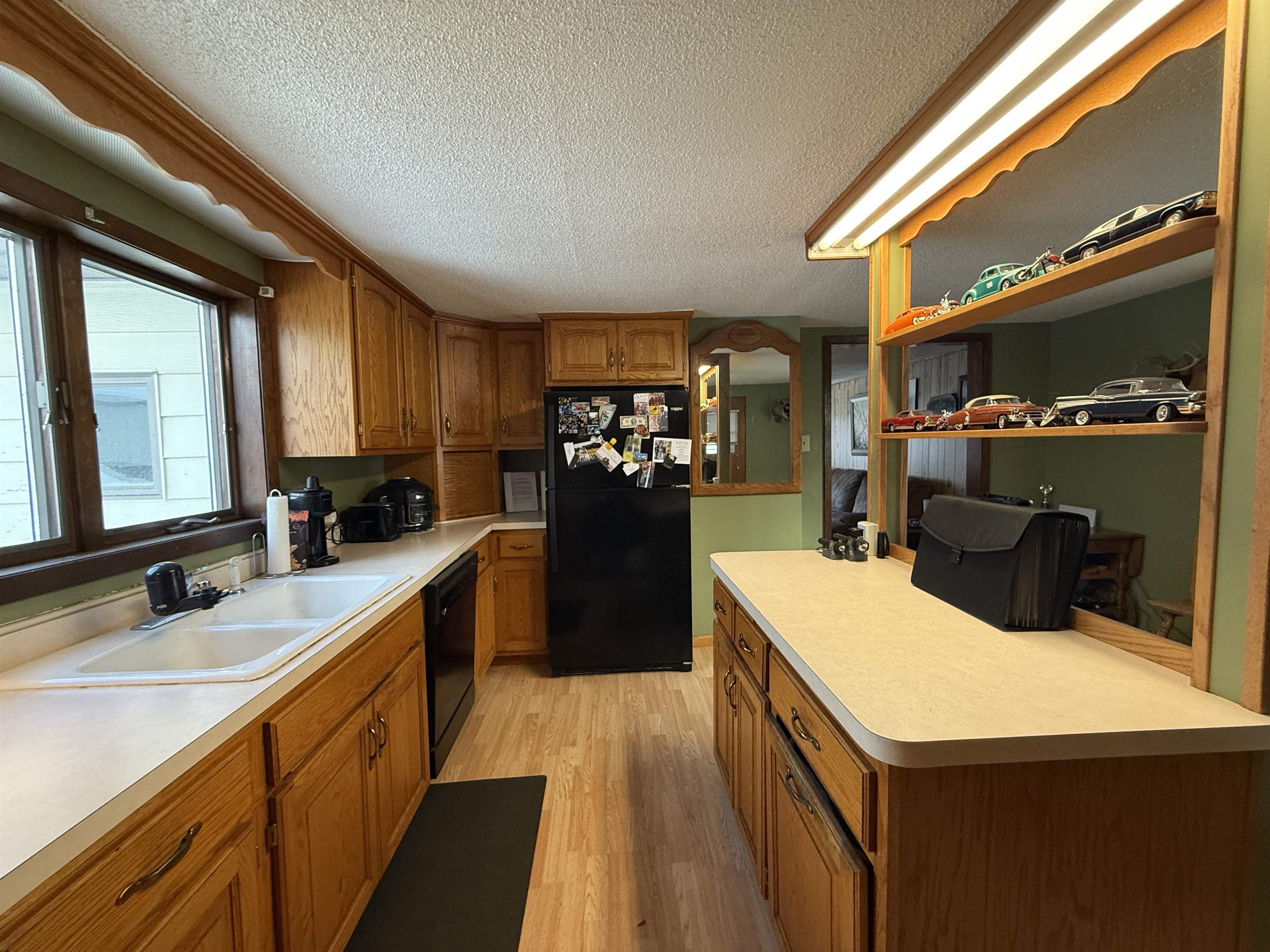 609 8th Street Northwest Chisholm, MN 55719 - Photo 9 of 26 Kitchen featuring brown cabinetry, black appliances, a textured ceiling, light wood-type flooring, and light countertops