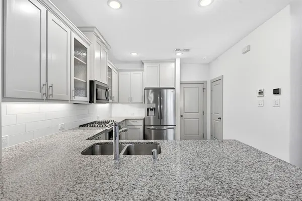 a kitchen with cabinets stainless steel appliances a sink and wooden floor