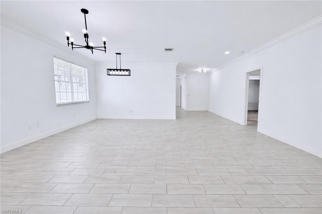 183 7th Street Naples, FL 34113 - Photo 5 of 50 Entry and living room featuring crown molding, tiled floors, and large windows providing ample natural lighting