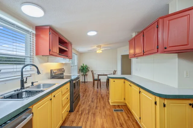 a kitchen with stainless steel appliances granite countertop a sink a stove cabinets counter space and a window