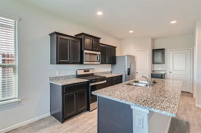a kitchen with kitchen island granite countertop a sink stove and refrigerator