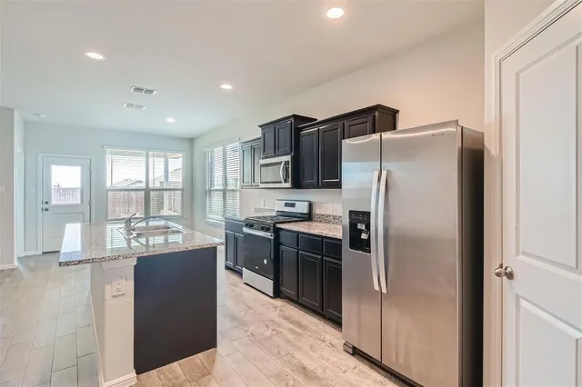 a kitchen with kitchen island a counter top space cabinets stainless steel appliances and a window