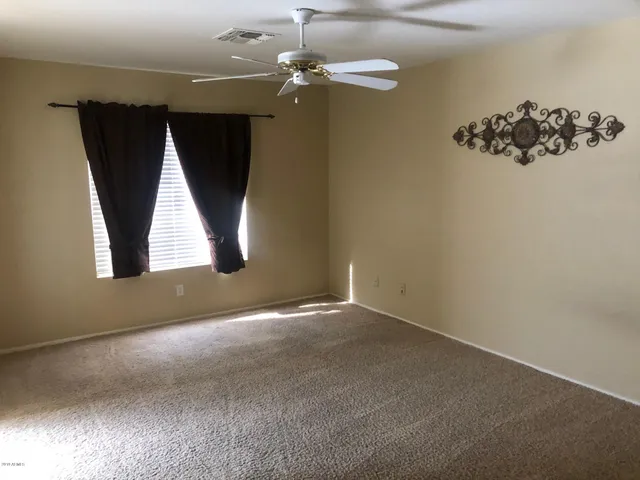 an empty room with windows and fan