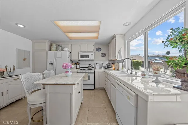 a kitchen with a sink dishwasher stove and white cabinets with wooden floor