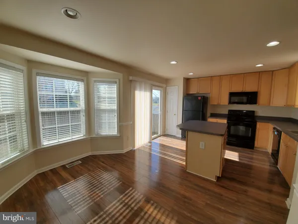a view of kitchen with microwave a refrigerator and wooden cabinets