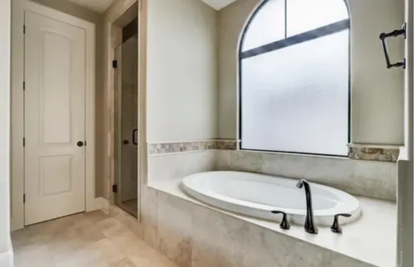 a bathroom with a tub a mirror and a shower