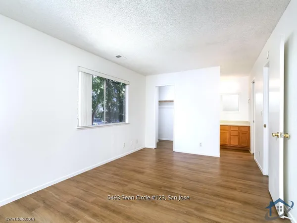a view of an empty room with wooden floor and a window