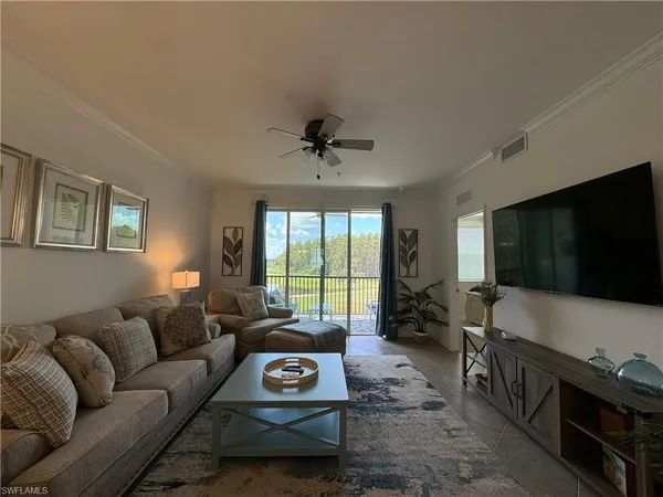 a living room with furniture a flat screen tv and a large window