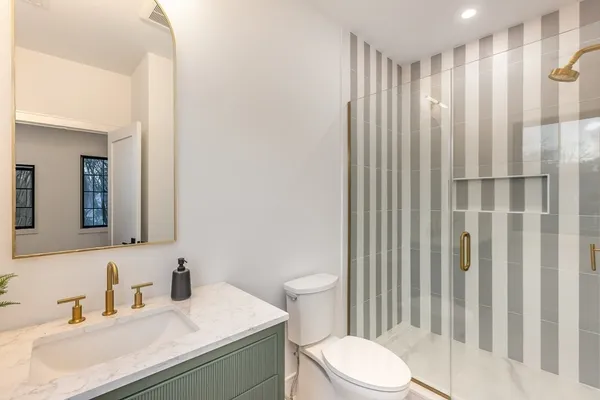 a bathroom with a sink a toilet and shower