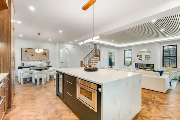 a large kitchen with a counter space a sink appliances and living room view