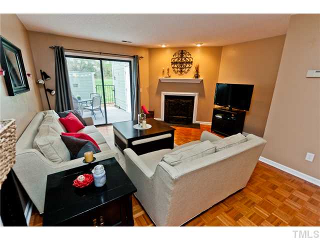 Light Filled Living Room with Wood Burning Fireplace and View of Enclosed Patio!