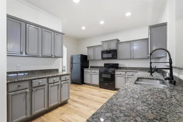 a kitchen with stainless steel appliances granite countertop a stove top oven a sink a refrigerator and white cabinets