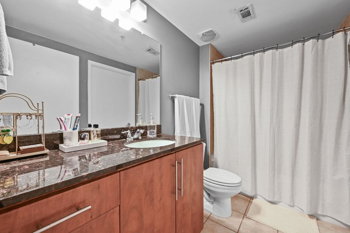 54 Rainey Street, Unit 416 Austin, TX 78701 - Photo 16 of 40 Full bathroom with light tile patterned floors, vanity, and a shower with shower curtain