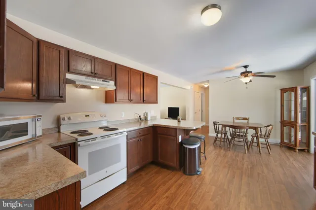 a kitchen with stainless steel appliances granite countertop wooden cabinets a stove a sink a dining table and chairs