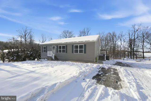 a front view of a house with a yard covered in snow