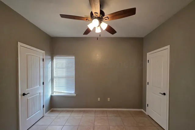 a view of an empty room with window chandelier fan and fire place