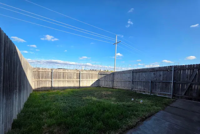 a view of a backyard with plants and wooden fence